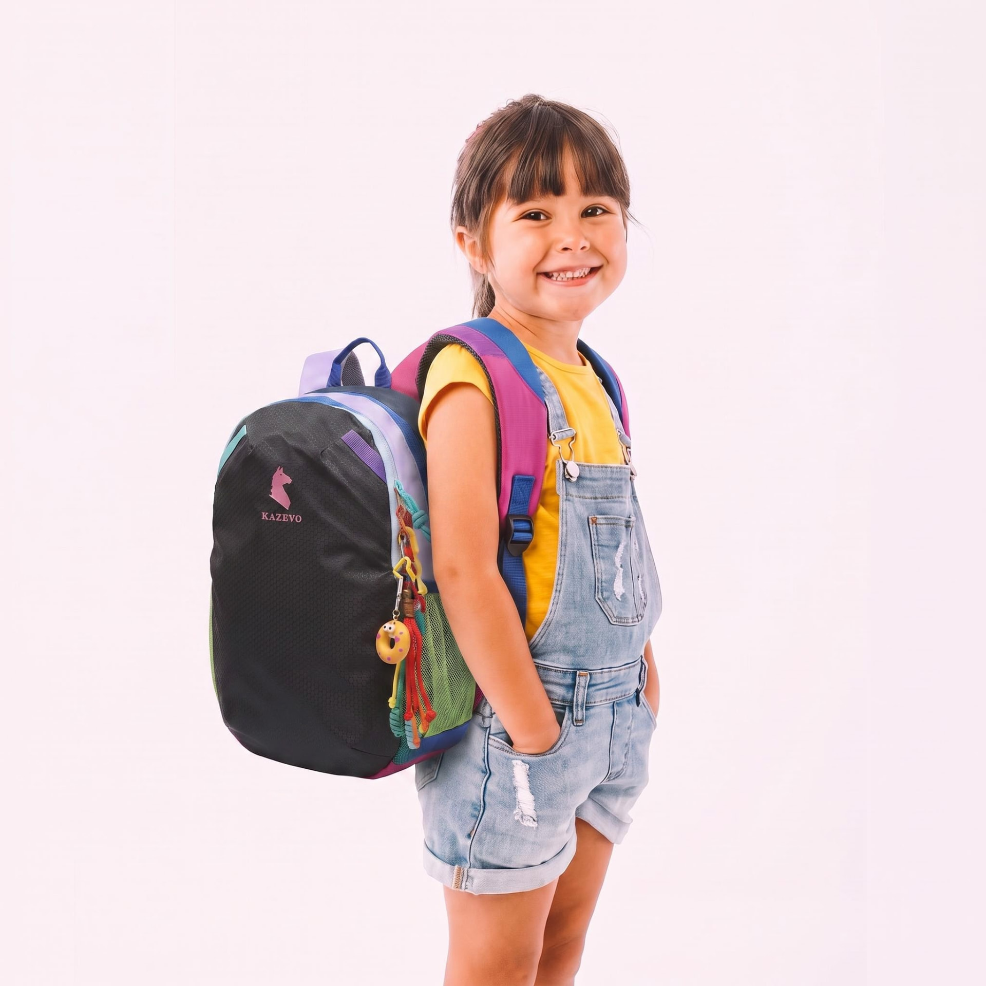 Young girl in dungarees smiling with a kazevo Mini backpack